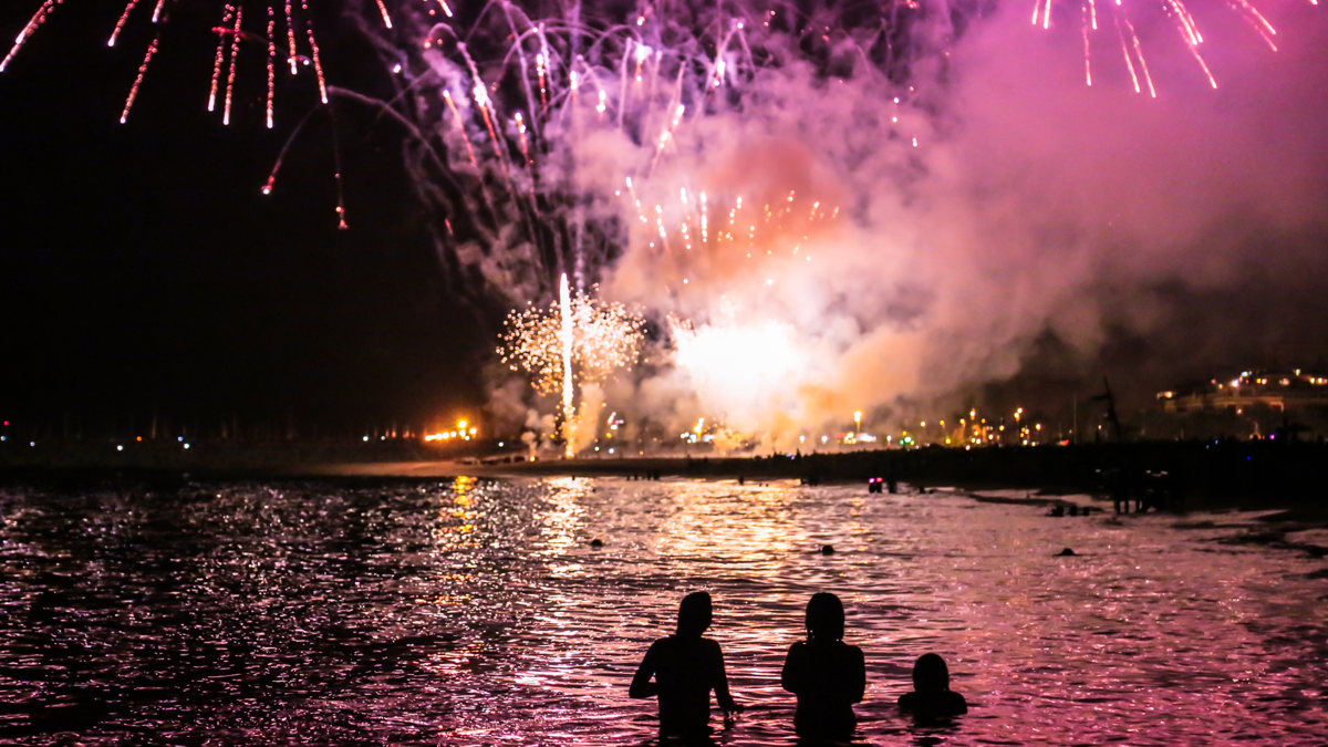 wading into ocean on New Year's Eve with fireworks in the background New Year's Eve traditions