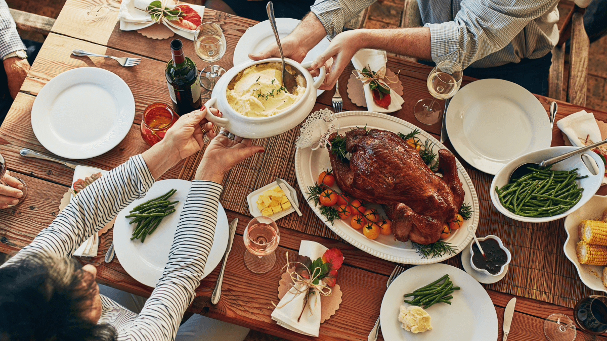 Food etymology represented by an overhead shot of a Thanksgiving meal, with people passing a carafe of mashed potatoes.