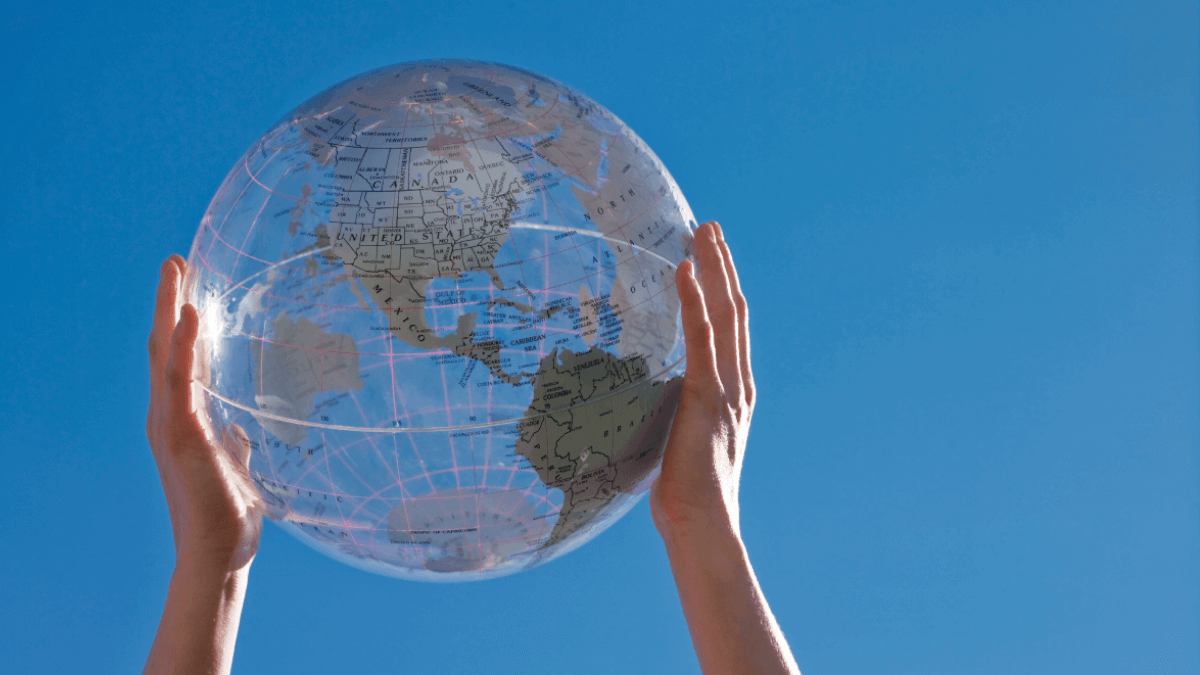 A person holding a clear globe to represent the most spoken languages in the world