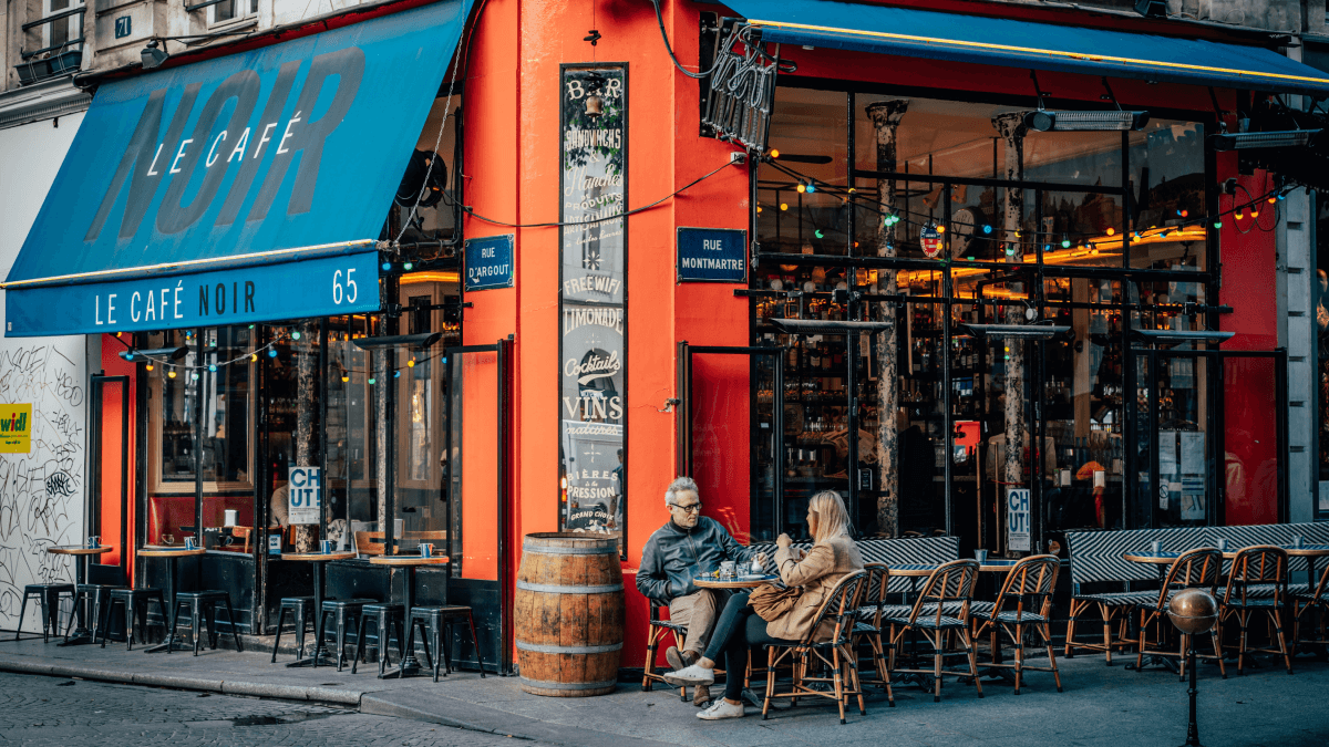 two people sitting on a parisian street corner french r