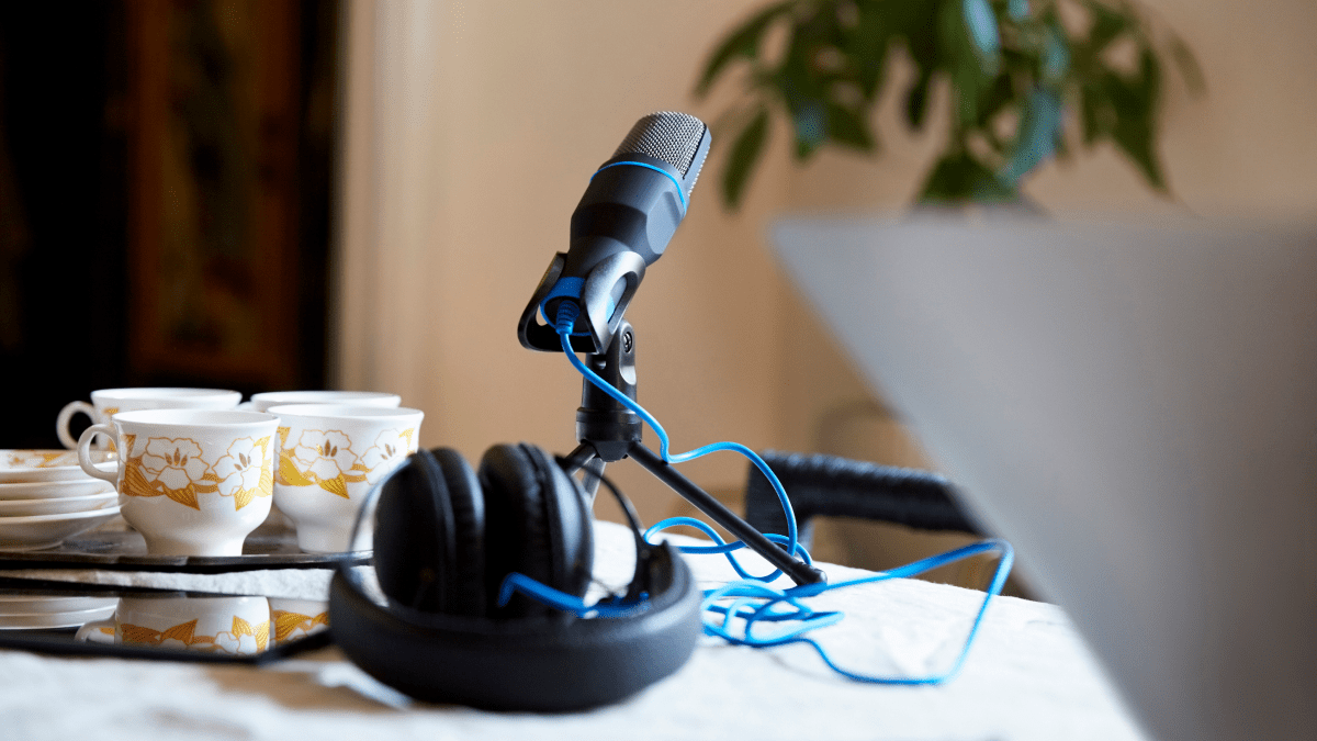 podcast microphone and headphones set up on a table with a laptop and teacups words of 2021