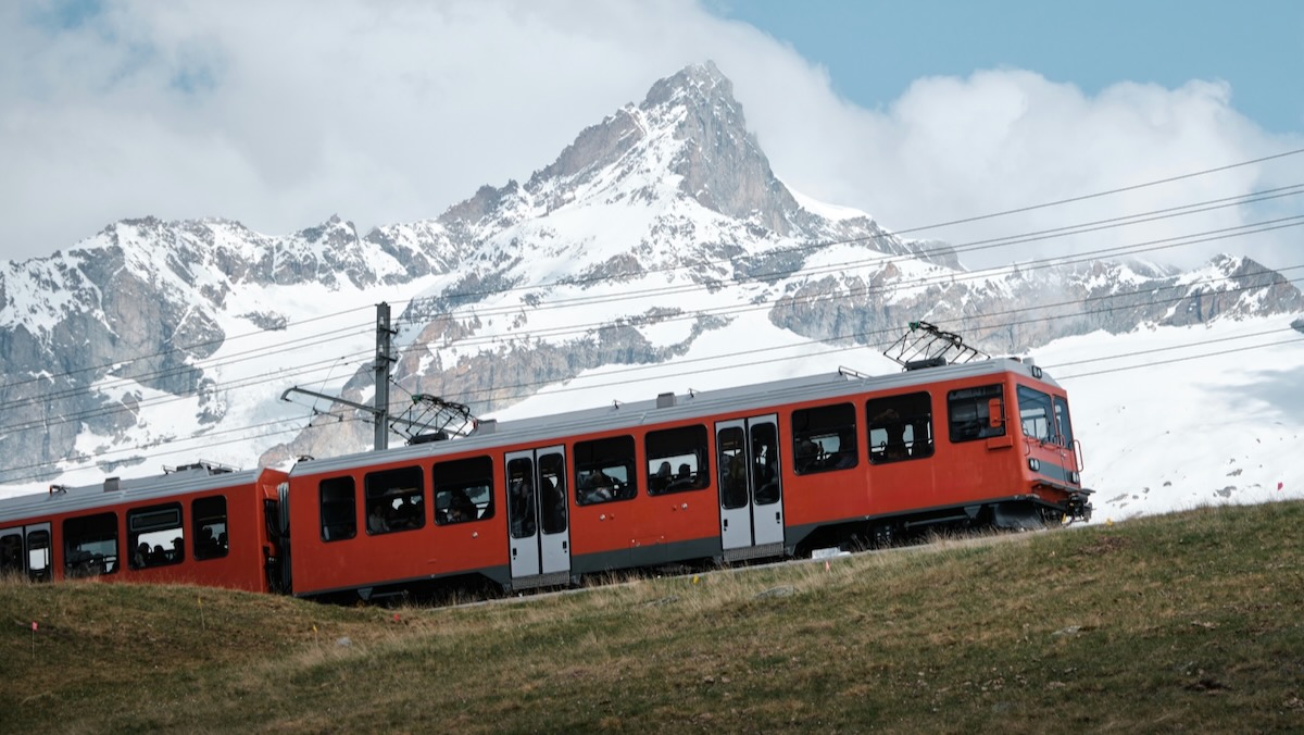 Un treno rosso in Svizzera, con una montagna innevata sullo sfondo
