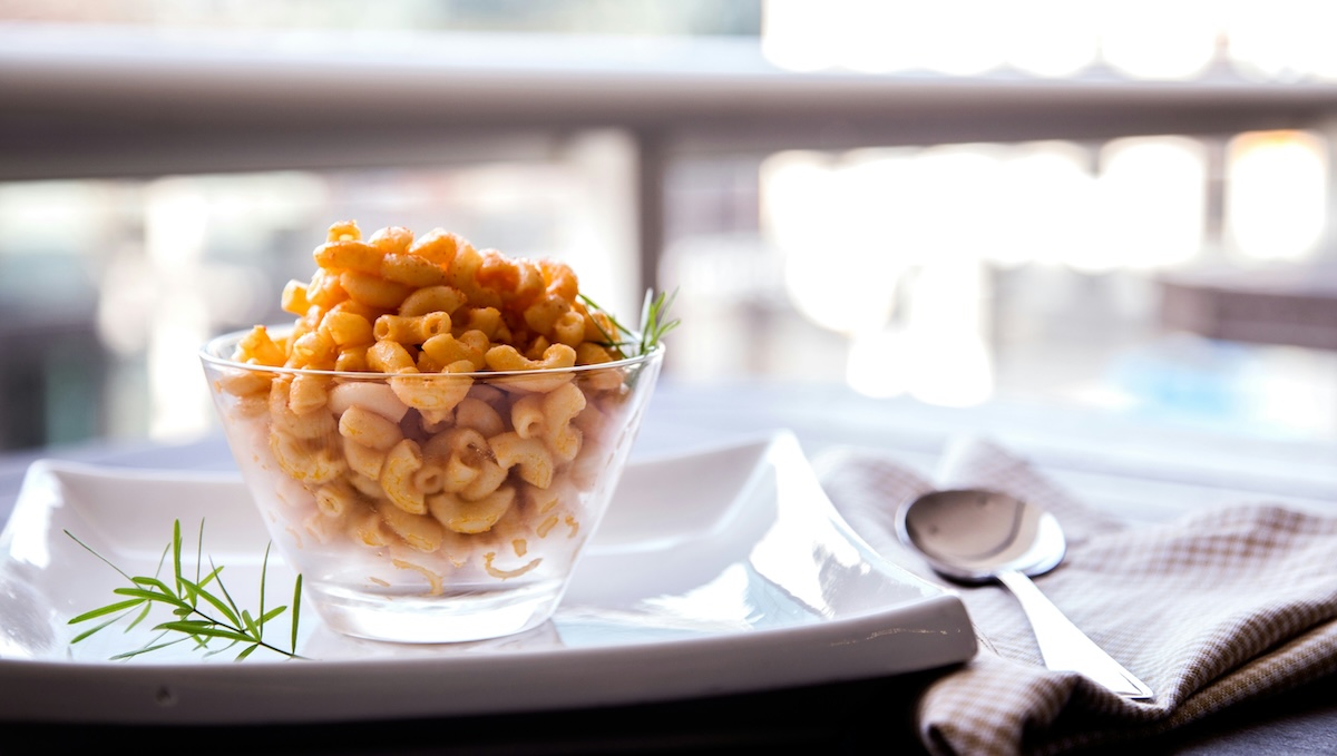 Glass cup filled with mac and cheese to represent macaronic language.
