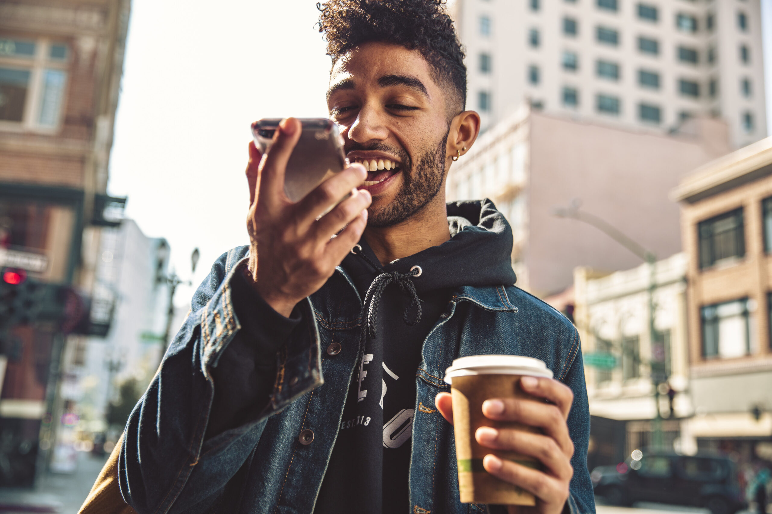 Mann mit Kaffee in der Hand spricht ins Handy