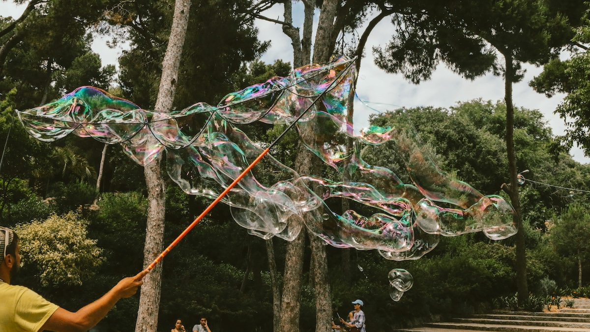 Por vs para represented by someone in Barcelona, Spain, making massive bubbles outdoors.